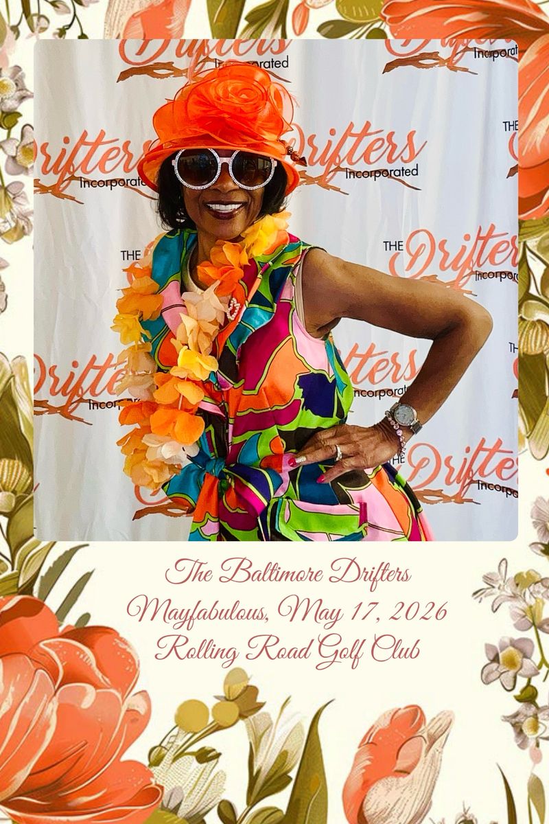 A woman in a bright orange hat, flower lei, and bold printed outfit posing at a club luncheon, on a floral photo layout
